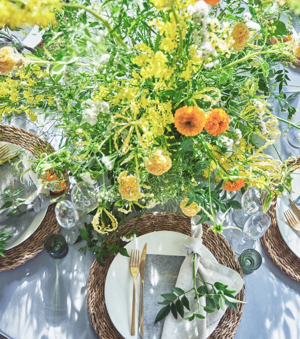 テーブル中央に黄色とオレンジの花が豪華に飾られた華やかなテーブル装花