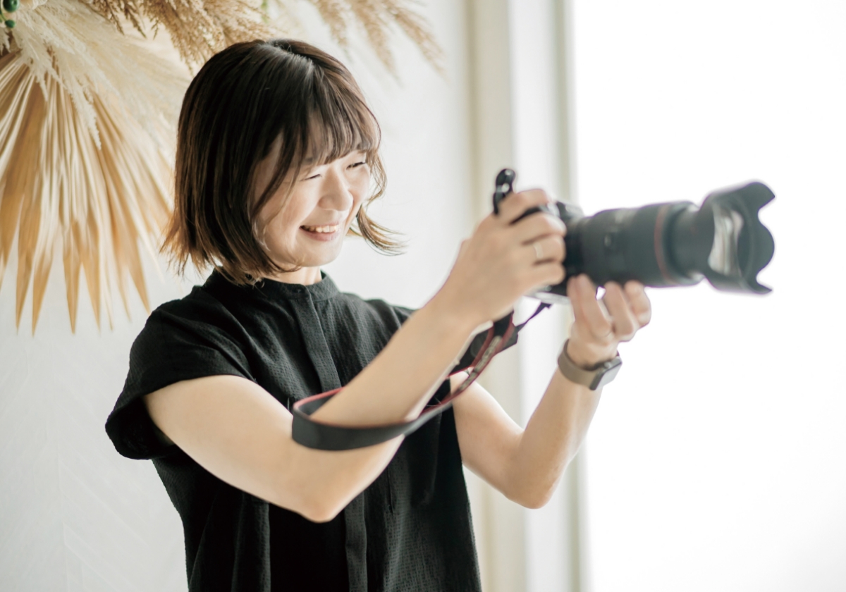 フォトグラファーが笑顔で一眼レフカメラを構えている様子