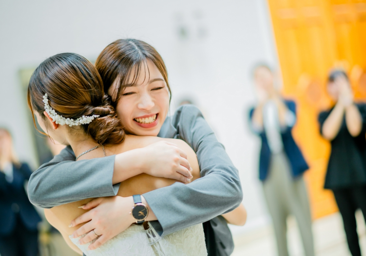 ウェディングドレス姿の花嫁とスタッフが笑顔で抱き合う感動的な瞬間