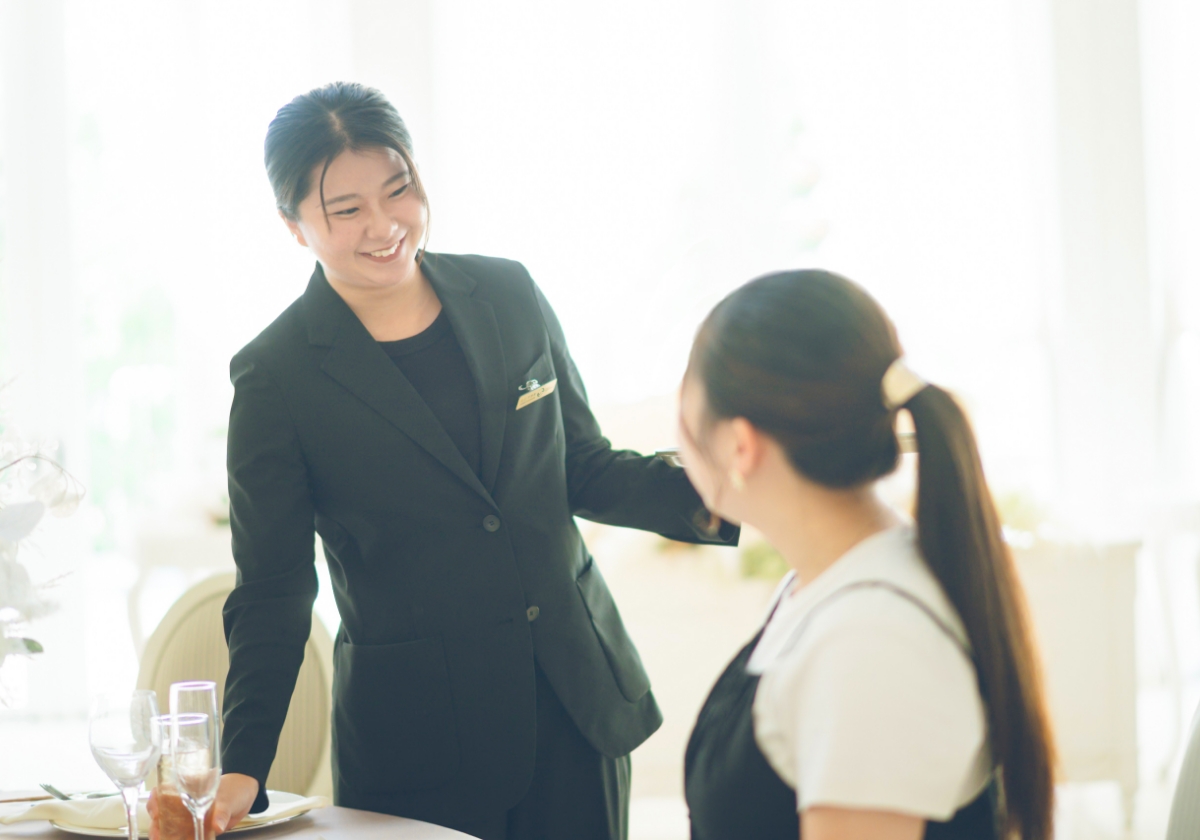 明るい披露宴会場で、丁寧な接客が行われている場面