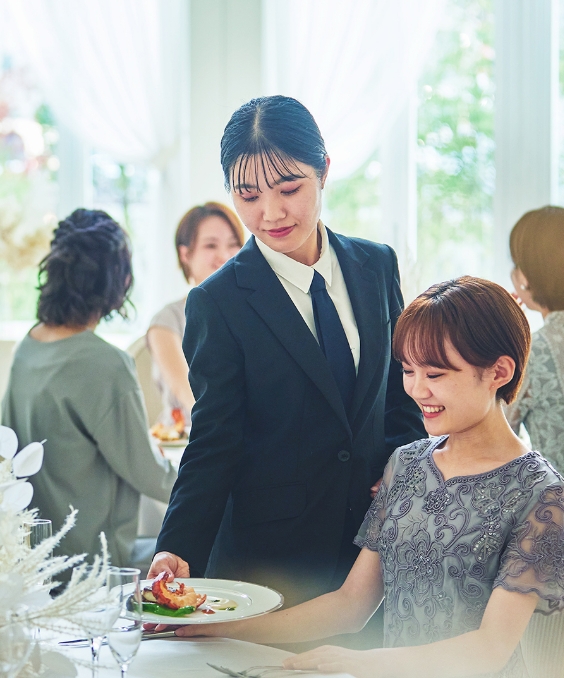 サービススタッフが披露宴のゲストに料理を丁寧に提供しているシーン